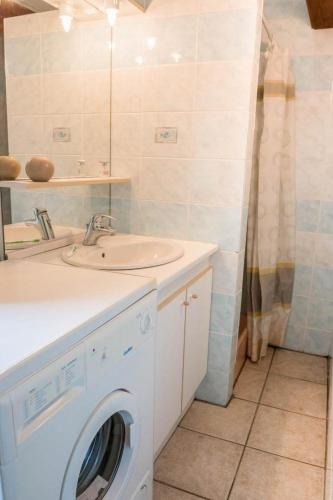 une salle de bain avec une machine à laver et un lavabo dans l'établissement Gite le finiels, à Bédouès