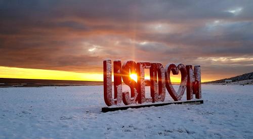 a stop sign in the snow with the sunset in the background at Fewo Wellenreiter Usedom 200 m zum Strand mit Balkon Parkplatz Wlan in Ostseebad Karlshagen