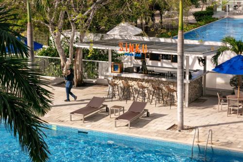 a person walking by a swimming pool next to a resort at Santa Marta Marriott Resort Playa Dormida in Santa Marta