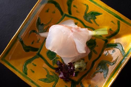a piece of meat on a yellow plate at まち宿 壱龍 MACHIYADO ICHIRYU in Takayama