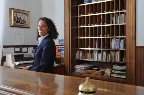 a woman standing behind a counter in a library at Grande Albergo Quattro Stagioni in Rieti