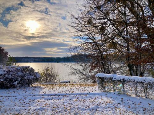 a snow covered bench next to a body of water at Tiny room in Langres