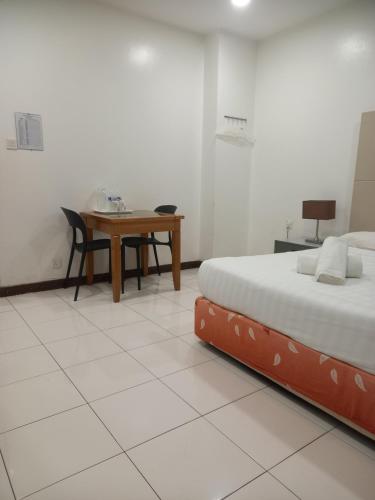 a bedroom with a desk and a bed and a table at Song Service Apartment formerly known as Jinhold Service Apartment in Kuching