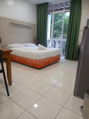 a bedroom with two beds and a table and a window at Song Service Apartment formerly known as Jinhold Service Apartment in Kuching