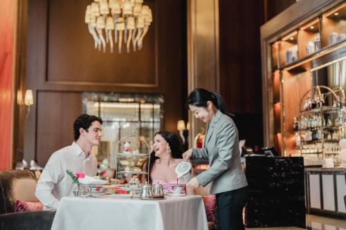a woman serving a man at a table in a restaurant at The Langham, Shenzhen in Shenzhen