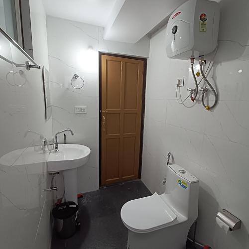 a small bathroom with a toilet and a sink at Mudita Stays in Darjeeling