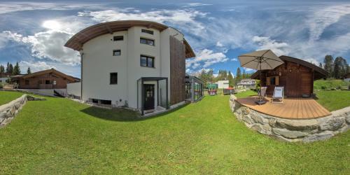 a small house with a wooden deck in the grass at Mountainlodge in Leutasch