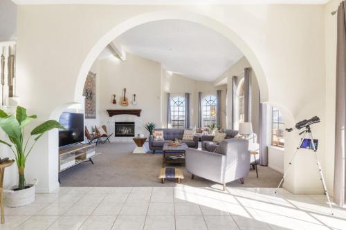 an arched living room with a couch and a tv at Summit House Joshua Tree Iconic Mountain Estate with Spa Ping-Pong Pool Table Fire Pit in Yucca Valley