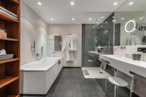 baño con bañera grande, 2 lavabos y espejo en AlpenParks Hotel & Apartment Taxacher, en Kirchberg in Tirol