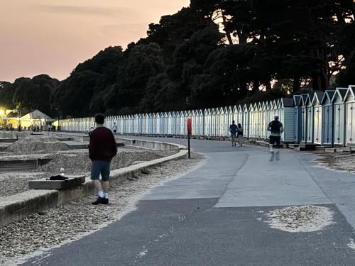 a group of people walking along a sidewalk next to a fence at Good Vibes in Christchurch