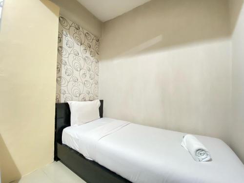 a small bedroom with a white bed and a window at Cozy 2BR Apartment at Pinewood Jatinangor By Travelio in Sumedang