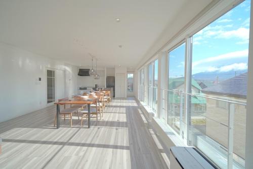 a dining room with a table and large windows at Glee Niseko LUX condo 羊蹄山一望 新築 駐車場完備 in Kutchan