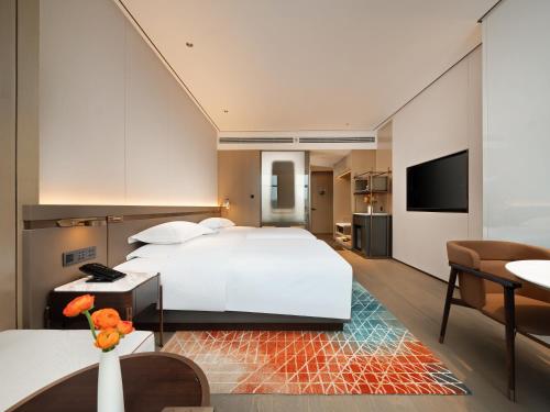 a bedroom with a large white bed and a living room at 成都中航明宇尚雅酒店 in Xindu