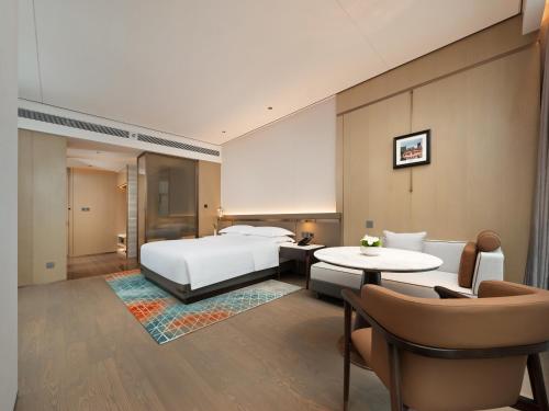 a hotel room with a bed and a table and chairs at 成都中航明宇尚雅酒店 in Xindu
