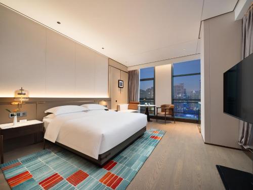 a bedroom with a large bed and a flat screen tv at 成都中航明宇尚雅酒店 in Xindu
