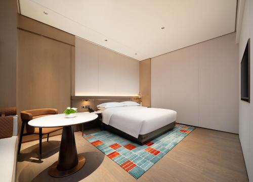 a bedroom with a bed and a table at 成都中航明宇尚雅酒店 in Xindu