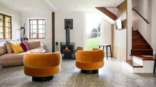 a living room with two orange chairs and a fireplace at Clergy Cottage in Taradale