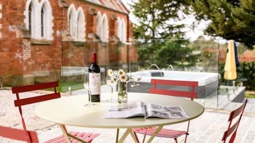 a table with a bottle of wine and flowers on it at Clergy Cottage in Taradale