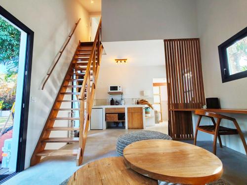 a living room with a wooden staircase and a table at COLIVER - COLIVING A LA RÉUNION in Saint-Pierre