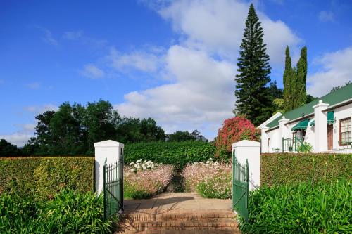 a garden with a gate and a house at The Cellars-Hohenort in Cape Town