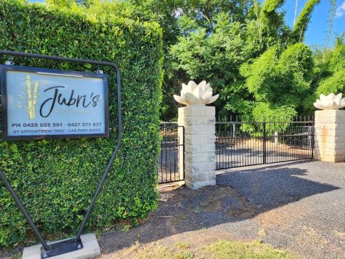 a sign in front of a bush with a gate at Jubri's Hideaway in Dalby