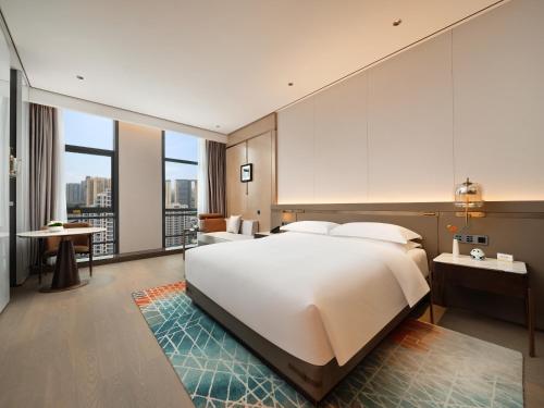 a bedroom with a large white bed and a large window at 成都中航明宇尚雅酒店 in Xindu