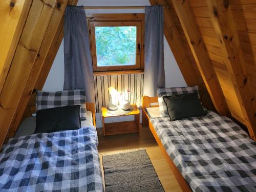 an attic room with two beds and a window at Chaty Kaszubskie in Łąkie