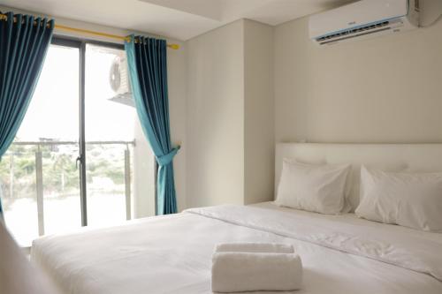 Un dormitorio con una cama blanca y una ventana grande. en Elegant and Comfy Studio at Daan Mogot City Apartment By Travelio, en Yakarta
