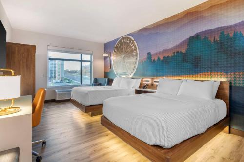 a hotel room with two beds and a painting on the wall at Cambria Hotel Pigeon Forge in Pigeon Forge