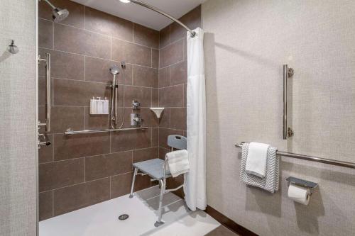 a bathroom with a shower with a chair in it at Cambria Hotel Pigeon Forge in Pigeon Forge