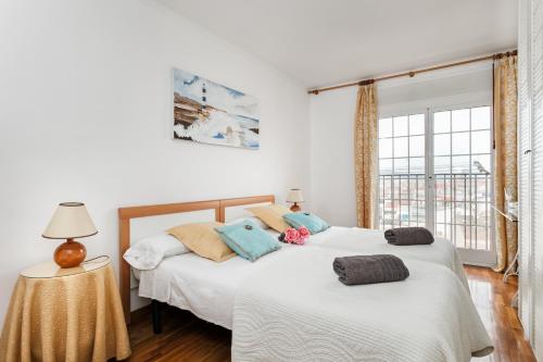 two beds in a white room with a window at Matarolux 2 in Mataró