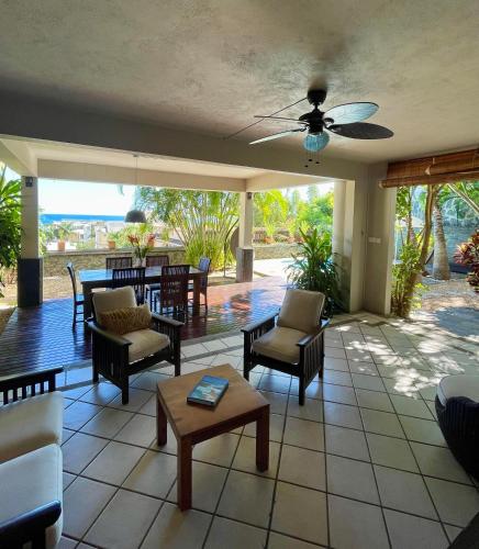 a porch with chairs and tables and a ceiling fan at Palm Nest in Rivière Noire