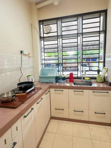 a kitchen with white cabinets and a sink and a window at Villa 2bedroom 14min Sutera Mall&Paradigm&Legoland&5min Xin Wan Chay in Johor Bahru