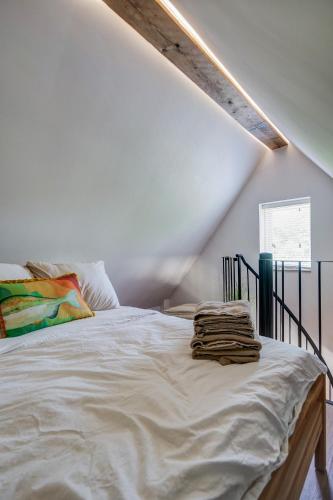 ein weißes Bett mit Handtüchern darauf in einem Zimmer in der Unterkunft Tiny Beachhouse Petten in Petten