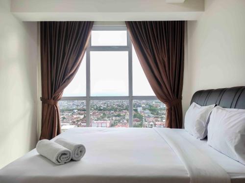 a bedroom with a large window with towels on a bed at Big and Comfy 3BR at Vida View Apartement By Travelio in Pampang