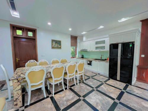 a kitchen with a table and chairs and a black refrigerator at Flamigo Dai Lai Resort - Happy Villa in Ngọc Quang
