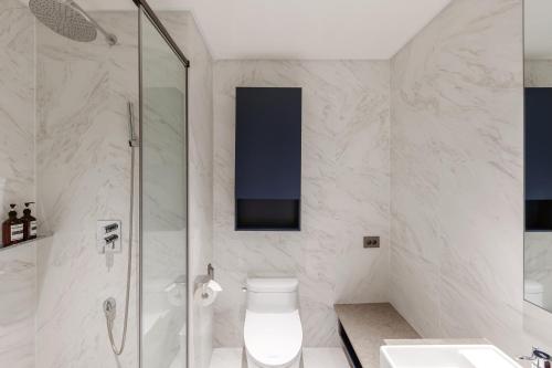a bathroom with a shower and a toilet and a sink at NewCZ Haeundae Residence in Busan