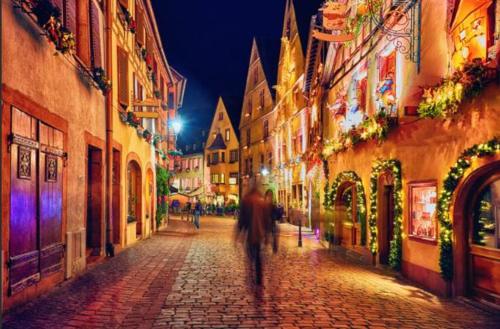 a man walking down a cobblestone street at night at Le Gîte de Jade in Dannemarie