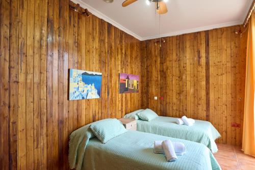 two beds in a room with wooden walls at Villa Santa Ana en La Carlota in La Carlota