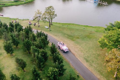 an old pink car driving down a road next to a park at Flamigo Dai Lai Resort - Happy Villa in Ngọc Quang