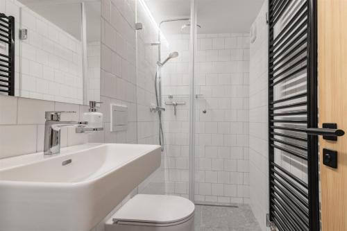 a white bathroom with a sink and a toilet at Pilnikárna in České Křižánky