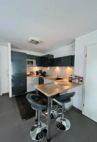 - une cuisine avec une table en bois et des tabourets de bar dans l'établissement Robertsau, jardin en ville, à Strasbourg