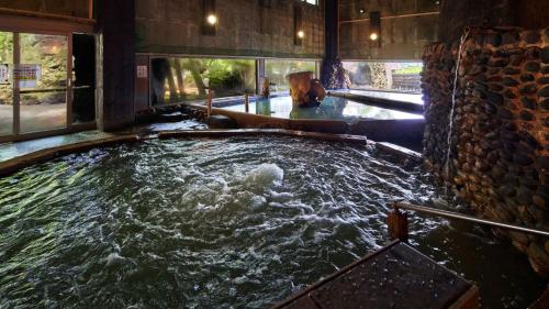 a jacuzzi tub in a building with water at Aso Baien Spa Resort in Minami Aso