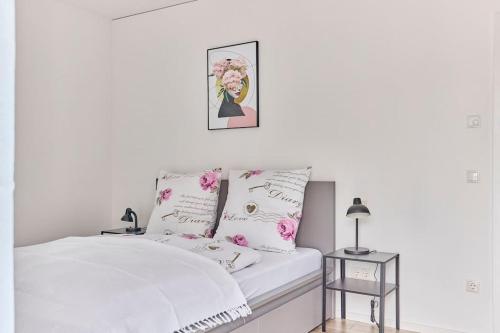 a white bedroom with a white bed with pink flowers at Zentral und ruhig Netflix Balkon Parkplatz in Bruchsal