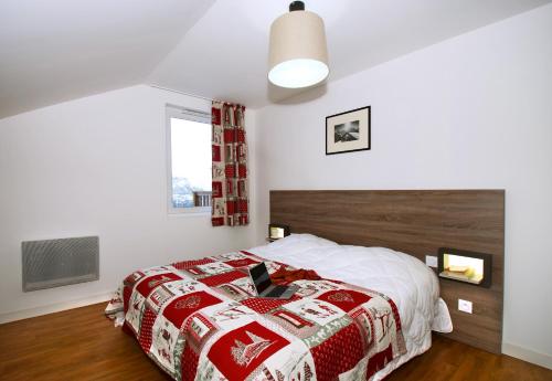 a bedroom with a bed with a red and white blanket at Résidence Odalys Les Balcons d'Auréa in Auris