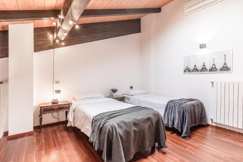 two beds in a room with white walls and wood floors at [Chardonnay]- elegante appartamento in Cavezzo