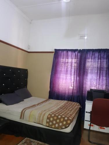 1 dormitorio con cama y cortinas moradas en Room Parow, Cape Town, en Cape Town
