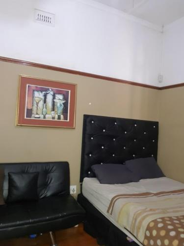 Un dormitorio con una cama con cabecero negro. en Room Parow, Cape Town, en Cape Town