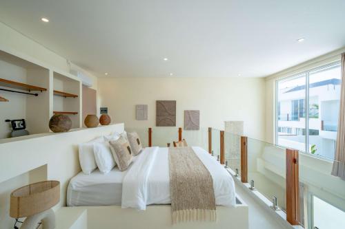 a white bedroom with a bed and a large window at Lyma Loft Pererenan in Canggu