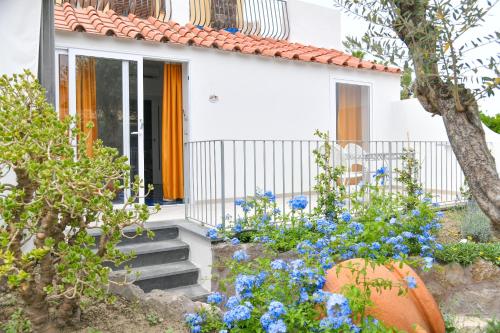 a white house with orange curtains and blue flowers at Hotel Terme Principe in Ischia